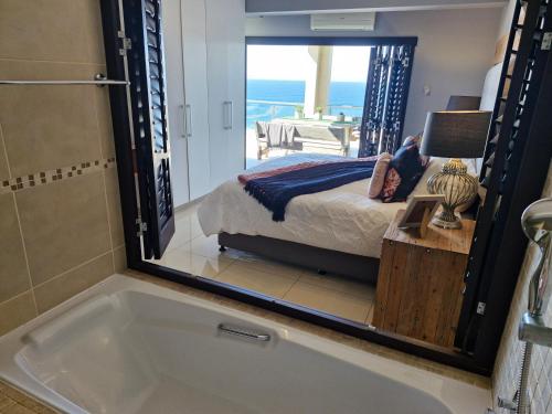 a bathroom with a tub and a bed and a bedroom at Whale Rock, Margate by MRL in Margate