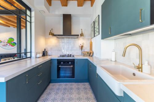 een keuken met blauwe kasten en een wastafel bij Rio Tío Cocinas in La Granja de San Ildefonso