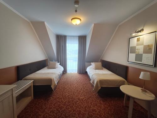 een hotelkamer met twee bedden en een tafel bij Pensjonat Cezar in Siemiatycze