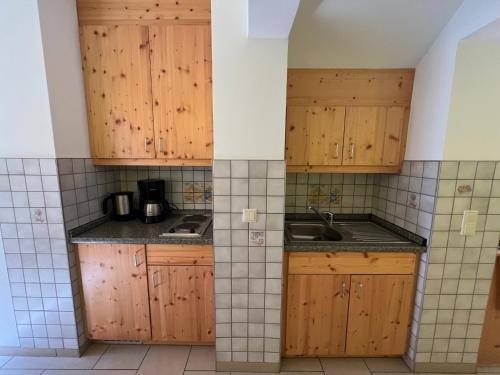 a kitchen with wooden cabinets and a sink at Pension Ostrauer Mühle in Bad Schandau