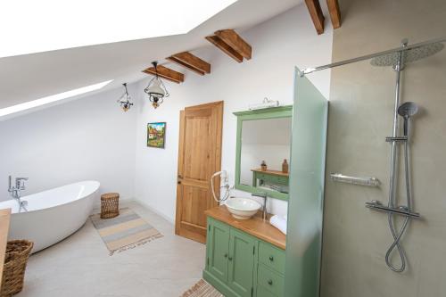 a bathroom with a tub and a sink and a shower at Pensiune Old Barn House in Vàrhegy