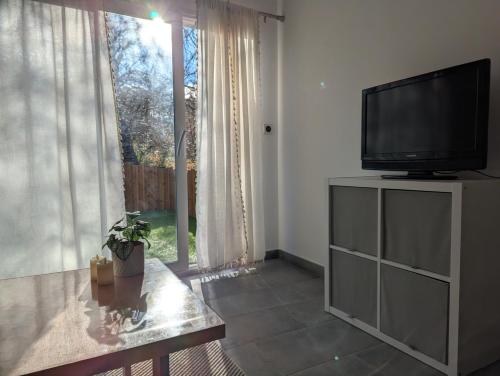 a living room with a flat screen tv and a window at Les Nuits Nordiques in Bras