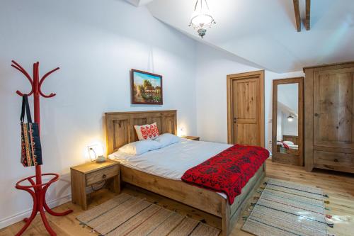 a bedroom with a wooden bed with a red blanket at Pensiune Old Barn House in Vàrhegy