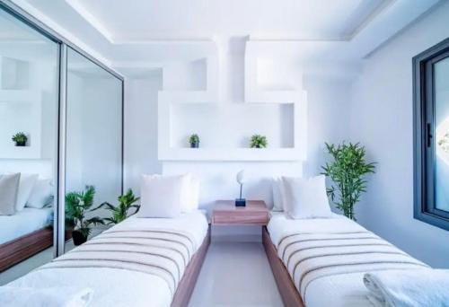 two beds in a room with white walls and windows at Appartement luxe hivernage in Marrakesh