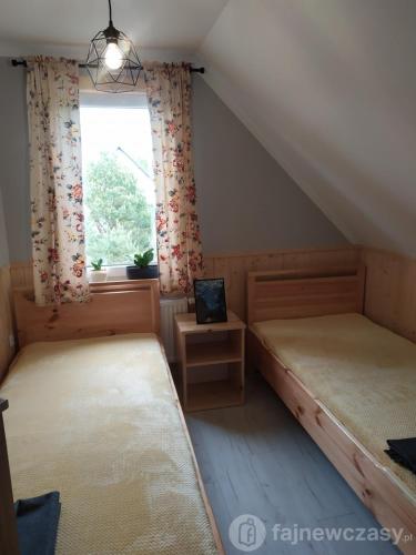 a room with two beds and a window with a laptop at Dom nad jeziorem Serwy in Serwy