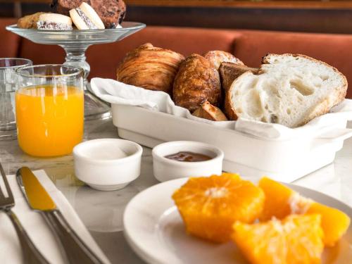a table with a plate of bread and orange juice at Costanero Hotel Montevideo - MGallery Collection in Montevideo