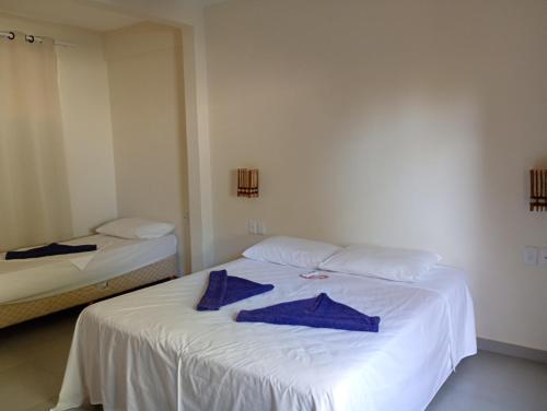 een slaapkamer met een wit bed en blauwe handdoeken. bij Pousada Caminho da Concha in Itacaré
