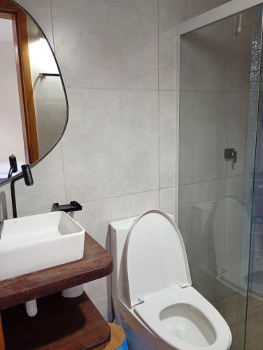 een badkamer met een toilet, een wastafel en een spiegel bij Pousada Caminho da Concha in Itacaré