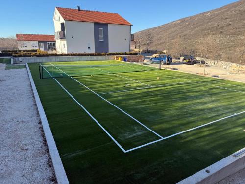 a tennis court with green grass on it at Vila Agape with a pool, football and tennis court in Lovreć