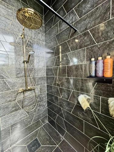 a bathroom with a shower with black tiles at Eagle Nest Eco Lodge in Sel