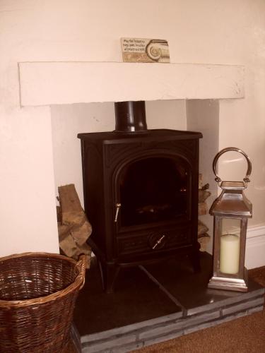 a fireplace with a stove and a candle and a basket at Invergarry Room Only Guest House For Adults in Windermere