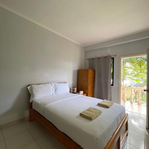 a bedroom with a large bed with two towels on it at Gold View Beachfront Resort in Timbaon