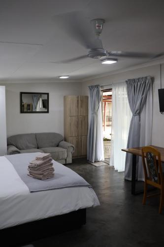 a bedroom with a bed and a couch at Kudu Kottage in Phalaborwa
