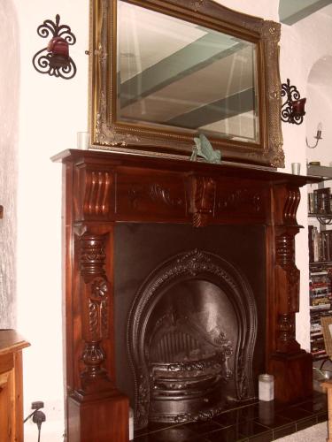 a fireplace with a mirror on top of it at Invergarry Room Only Guest House For Adults in Windermere