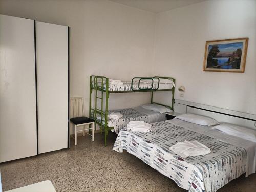 a bedroom with two bunk beds and a chair at HOTEL ROSSINI in Rimini