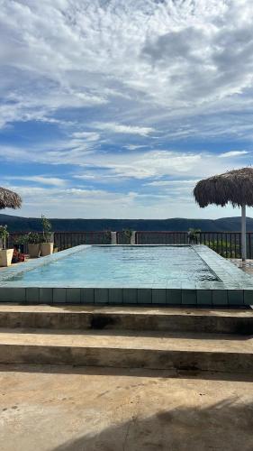 a swimming pool with stairs and two umbrellas at Villa carnaúbas in Pedro II