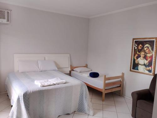 een witte slaapkamer met een bed en een stoel bij Pousada Utopia in Aparecida