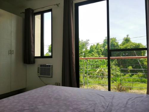 a bedroom with a bed and a large window at Silay Haven Near Airport by One Guest Place 3919B in Silay