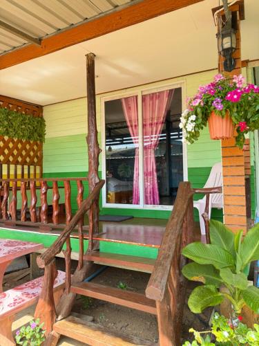 een veranda van een huis met een bank en bloemen bij KohLibong Beach House Homestay in Ban Batubute