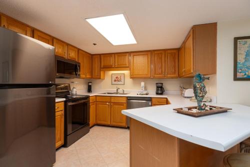 a kitchen with wooden cabinets and a stainless steel refrigerator at Phoenix East II 2033 in Orange Beach