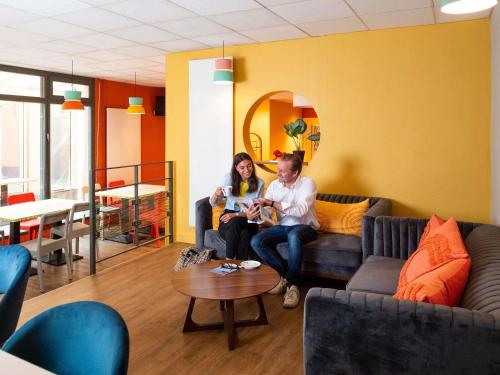 a man and woman sitting on a couch in a room at Adagio Access Lyon Centre Université in Lyon