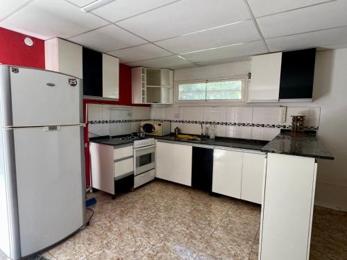 a kitchen with white appliances and red and white cabinets at Casa El Trapiche Lo Altos in Trapiche