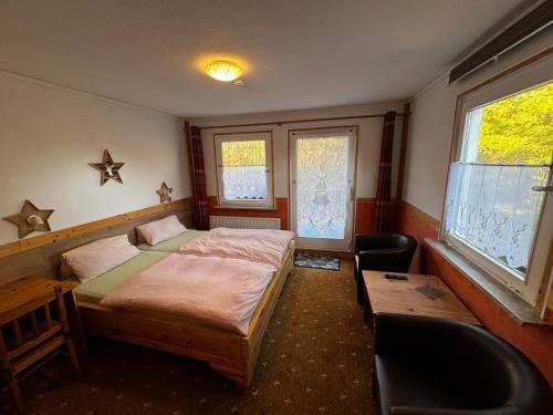 a bedroom with a bed and a chair and windows at Wald-Landhaus in Hahnenklee-Bockswiese