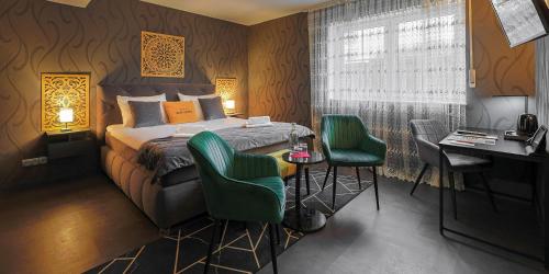 een slaapkamer met een bed en 2 groene stoelen bij DUA Hotel in Sarstedt