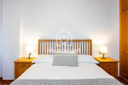 una camera da letto con un letto con lenzuola bianche e due lampade di El Pescador El Pris, by Nivariahost a El Pris