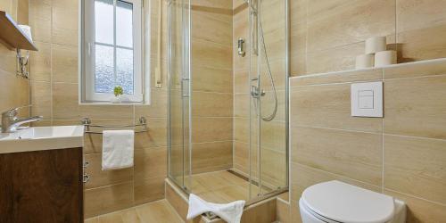 a bathroom with a shower and a toilet and a sink at DUA Hotel in Sarstedt