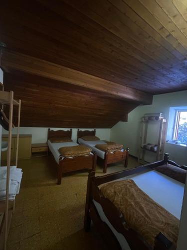 a room with three beds and a wooden ceiling at Rifugio La Capanna in Claviere
