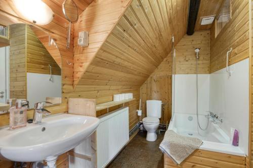 a bathroom with a sink and a tub and a toilet at Le Chalet Rustique in Spa