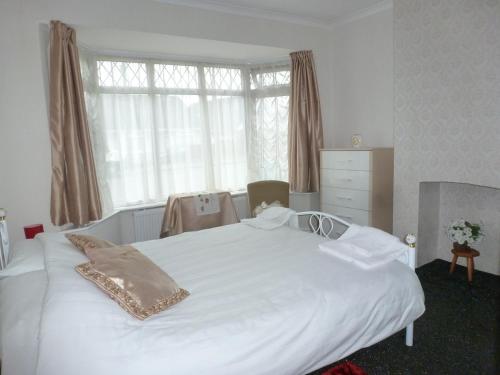 a white bed in a bedroom with a large window at Beautiful 'Rose-Dene' with ample parking in Sheerness