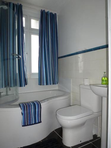 a bathroom with a toilet and a tub and a sink at Beautiful 'Rose-Dene' with ample parking in Sheerness