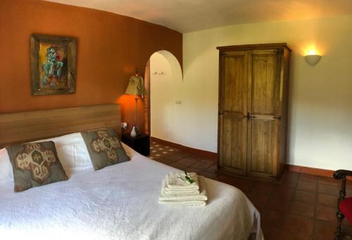 Schlafzimmer mit einem weißen Bett und einem Holzschrank in der Unterkunft Back to La Tierra, natural finca in Mijas in Mijas