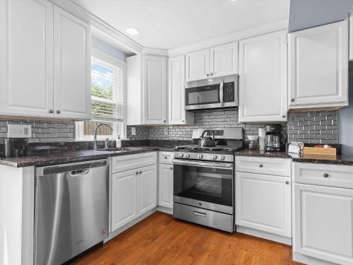 a kitchen with white cabinets and stainless steel appliances at NoMA 3BR Townhome - UnionMarket H St Streetcar in Washington, D.C.