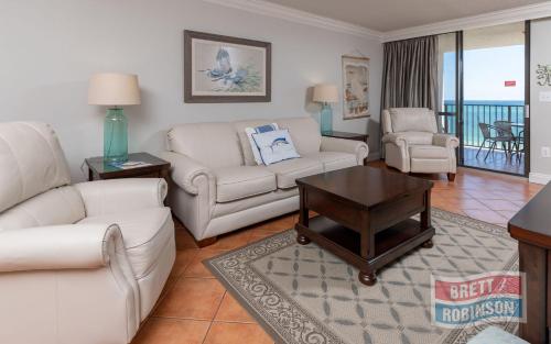 a living room with white furniture and a balcony at Phoenix East II 2072 in Orange Beach