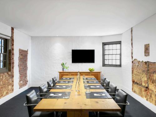 una grande sala conferenze con un lungo tavolo e sedie di Peppers Gallery Hotel a Canberra