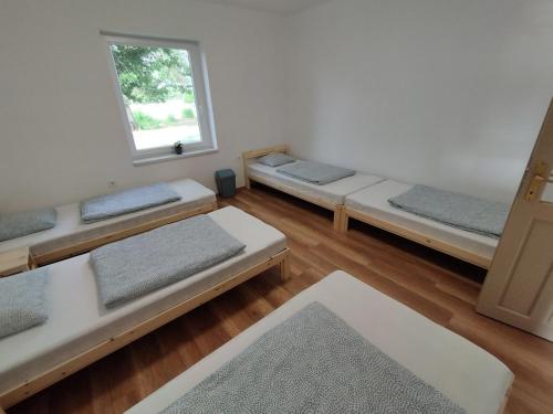 a room with three beds in it with a window at Napfény Tanya in Tázlár