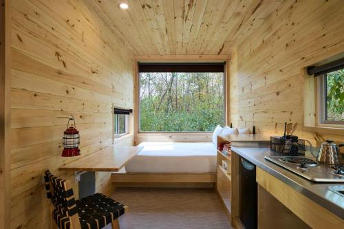 a log cabin kitchen with a large window and a bed at Postcard Cabins Starved Rock, Outdoor Collection by Marriott Bonvoy in Ottawa
