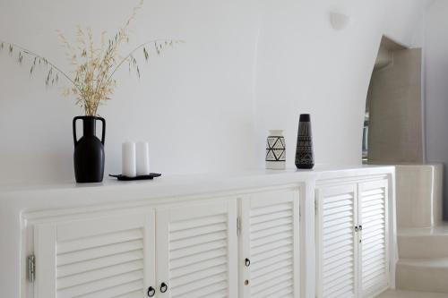 a white cabinet with vases and candles on it at Blue Art Caves in Oia