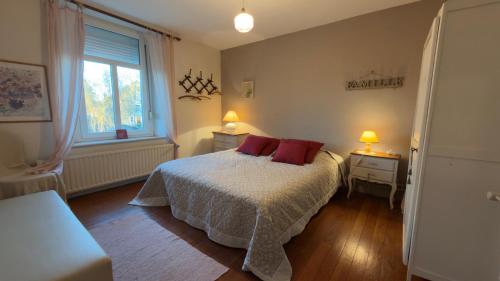 a bedroom with a bed with two red pillows on it at Le Pré en Bulles in Chiny