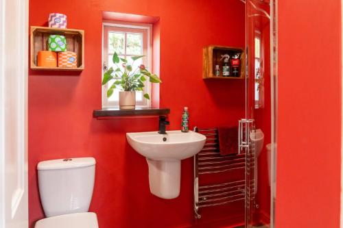 een rode badkamer met een toilet en een wastafel bij Garden Cottage at Old Post Office in Bardon Mill
