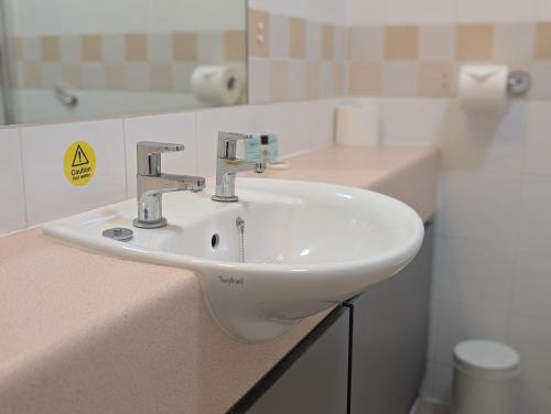 a white sink in a bathroom with a mirror at Hitchin Priory Inn in Hitchin