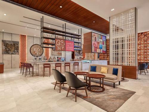a lobby with a bar and a couch and tables at Novotel Jaipur Convention Centre in Jaipur