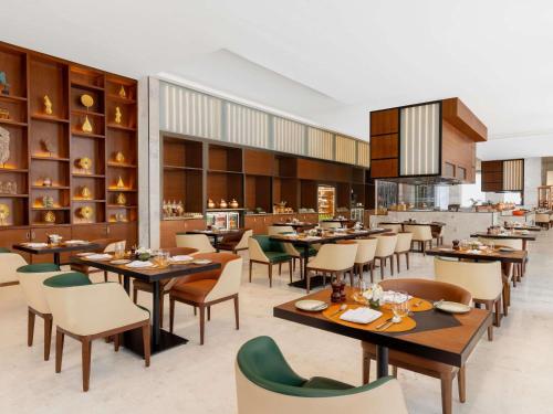a restaurant with tables and chairs in a room at Novotel Jaipur Convention Centre in Jaipur