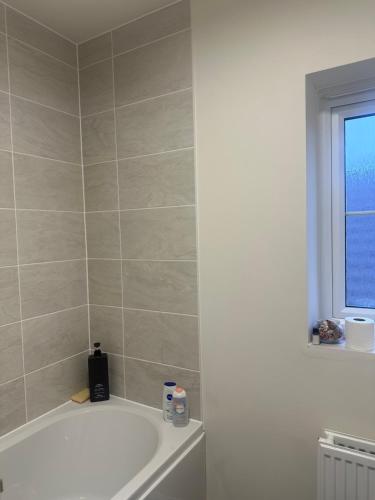 a bathroom with a bath tub and a window at The Calm Space Room in Balderton