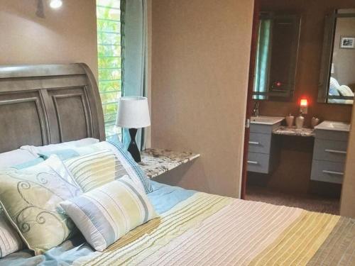 a bedroom with a bed and a bathroom with a sink at Superbe Zions Hill Views in Sion Farm