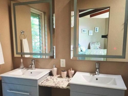 a bathroom with two sinks and a large mirror at Superbe Zions Hill Views in Sion Farm