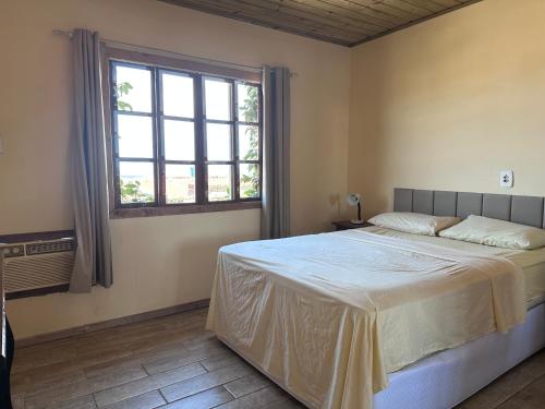 a bedroom with a large bed and a window at Casa Vila Nova Alvorada in Imbituba